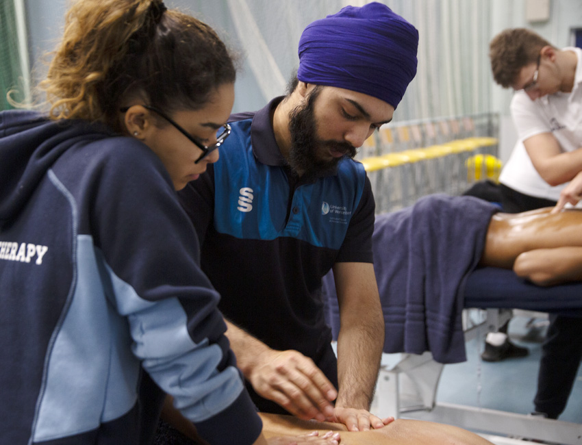 Two sports therapy students giving a massage as part of a practical activity