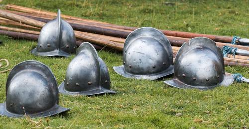 silver civil war helmets and wooden pikes lying on the grass