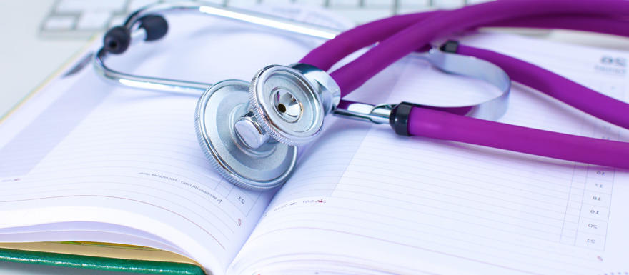 A purple stethoscope on top of medical notes.