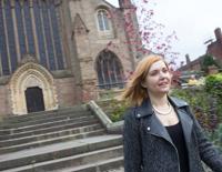 Woman walking down the steps of Worcester cathedral, wearing a leather jacket and black top