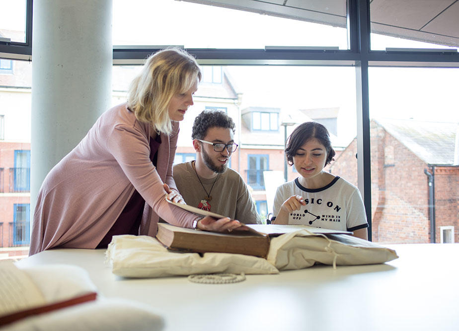 Three people looking at an historic book