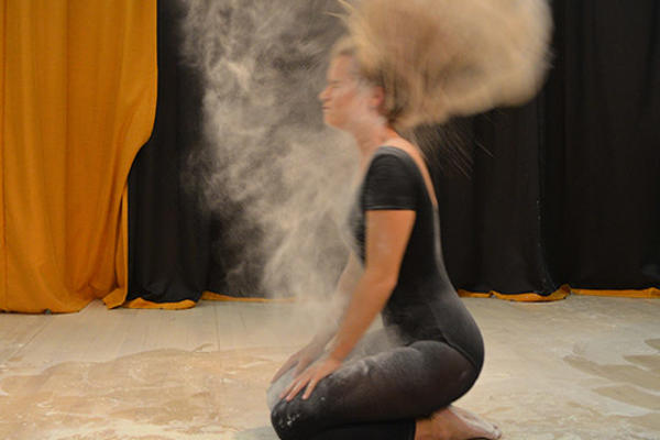 Female student in black throws hair back in cloud of dust