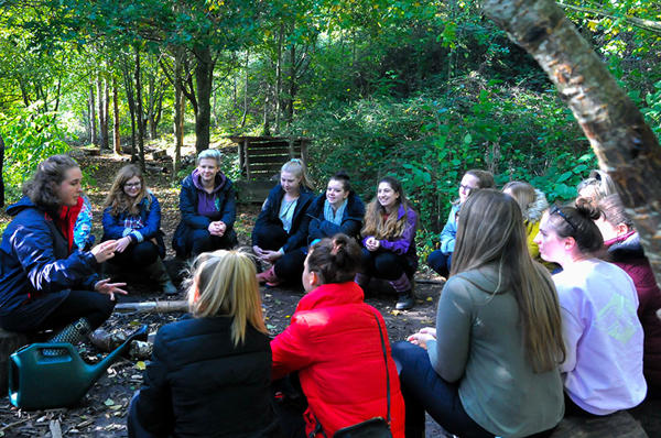 Group of Early Childhood in Society students in a circle in a wood