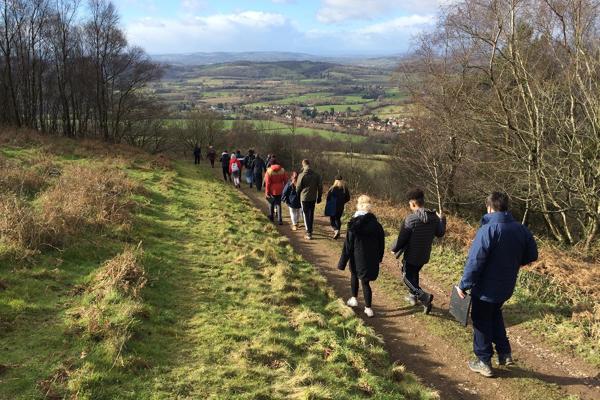 students on an outdoor path heading towards a group of hills