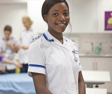 A female student is wearing a nurses uniform and is training to be a nurse is one of our clinical skills room used on our nursing degree.