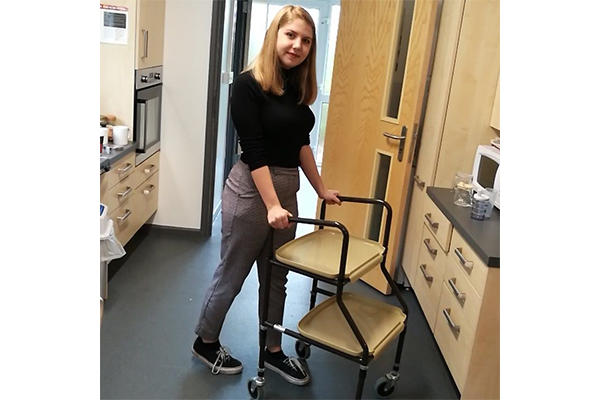 A female Occupational Therapy trainee walks with a frame as part of our Occupational Therapy degree.