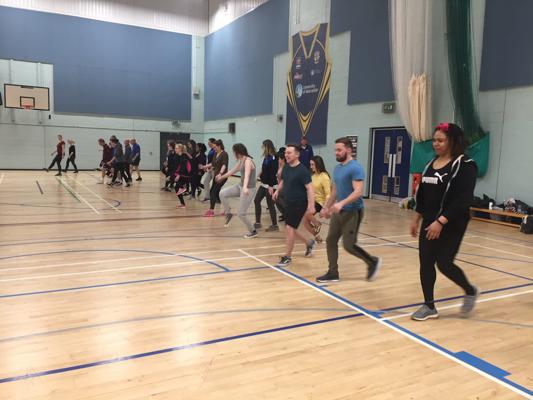 A group of student occupational therapists doing a walking exercise in the sports hall on our occupational therapy degree.