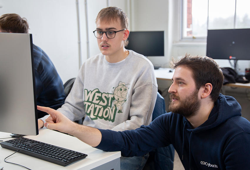 A lecturer supporting a student with a computer task
