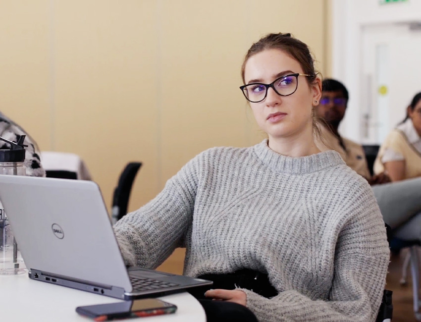 A girl listening to a lecture with a laptop on the desk