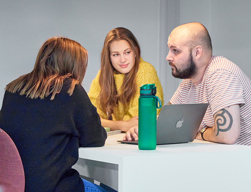 Three students working together on a laptop