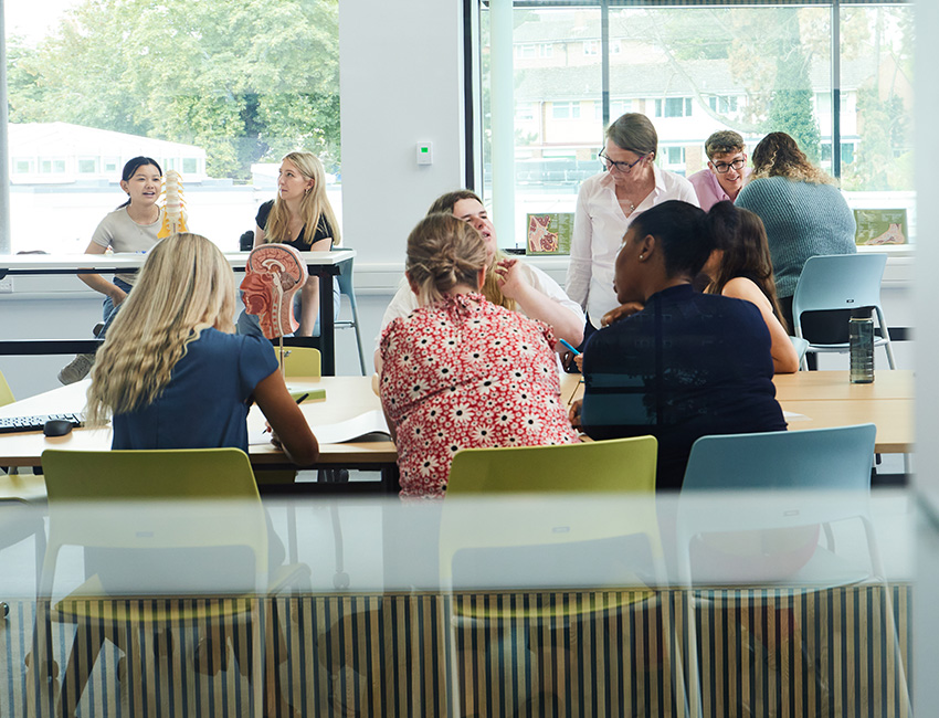 A group of students sat in a classroom, with a lecturer supporting the students at the front