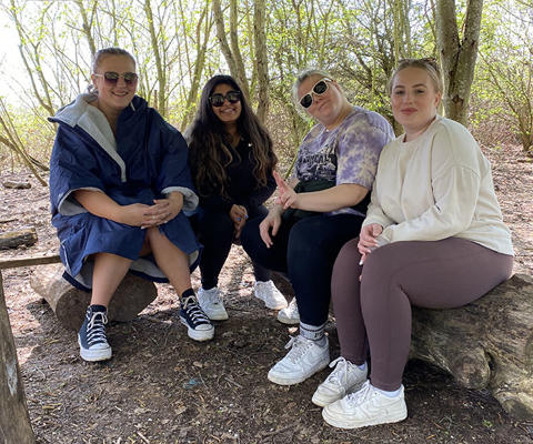 4 students are sitting on a log