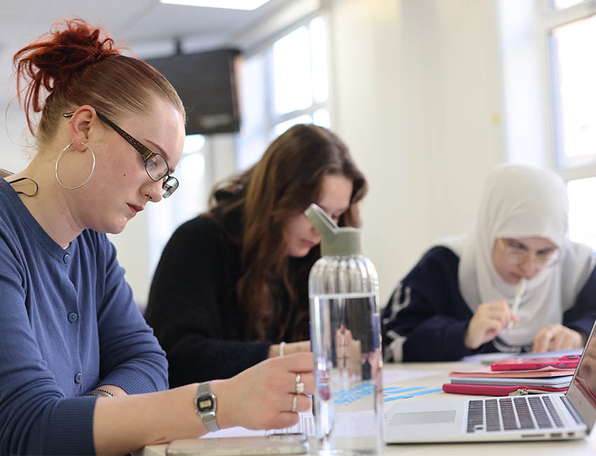 three students focussed on their work in the classroom