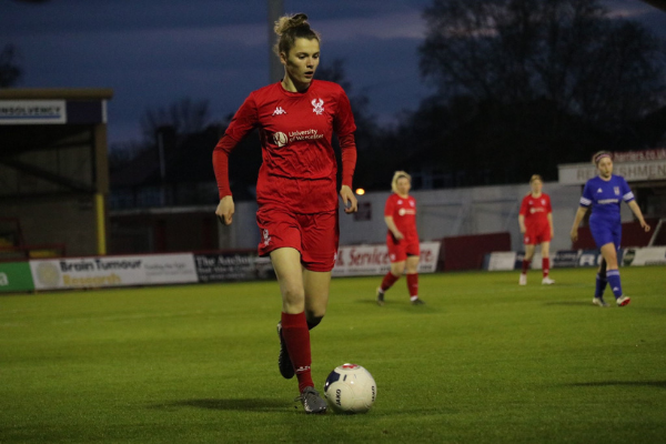 Player in red uniform kicking football with players in background