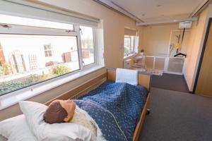 a dummy lying on a bed that is mostly covered with blue bed linen