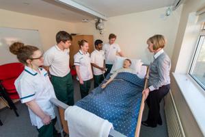 Five student nurses and a lecturer at the bedside of a synthetic patient