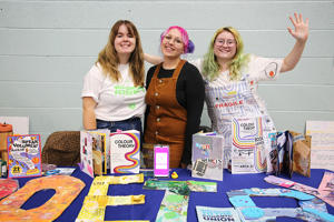 The Poetry society stall at the Welcome Fair with three students waving