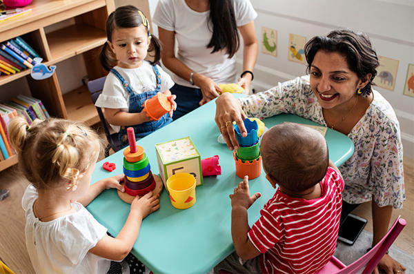 A teacher is sitting on the floor playing with children