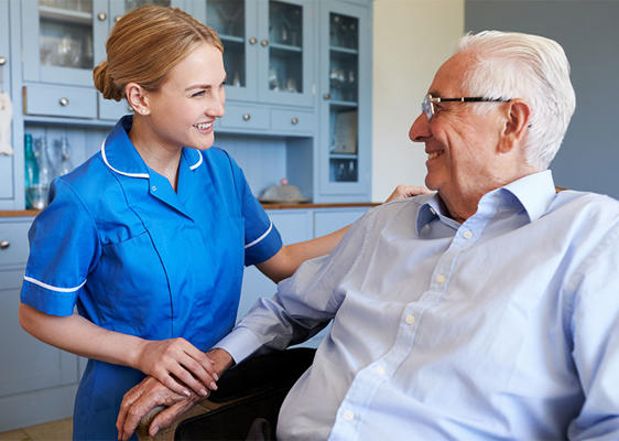 A nurse is speaking to a smiling older gentlemen