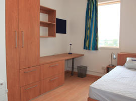 inside a bedroom including a brown cupboard and a window
