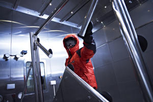man in a red protective suit inside a laboratory filled with angled metal posts