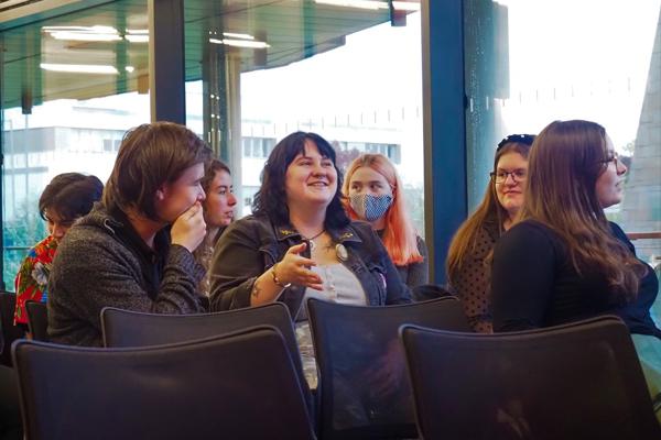 A number of students sitting down smiling at each other