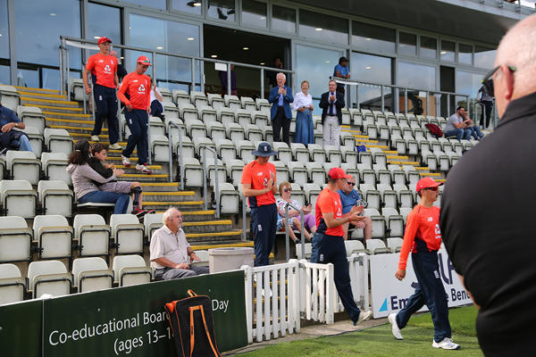cricketers descending the stairs towards the pitch