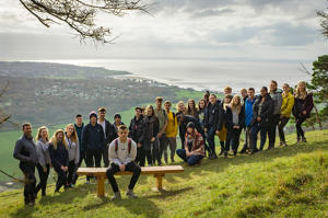 group photo of students with a sea view in the background