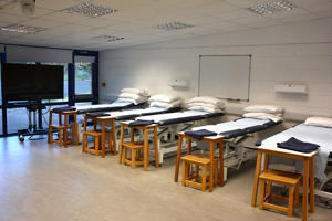a row of beds within a lecture room set out as a ward