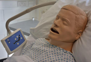 synthetic patient who is half-sitting with his head against a pillow