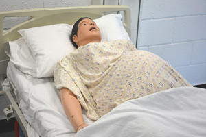 synthetic patient lying down with a bump to suggest pregnancy