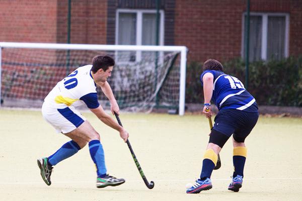 men playing hockey on an outside pitch