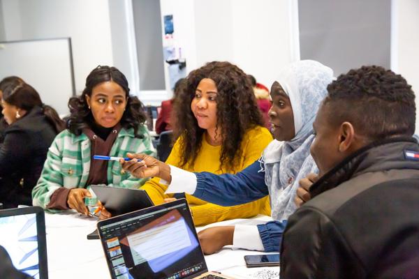 students around a table and one of them is pointing