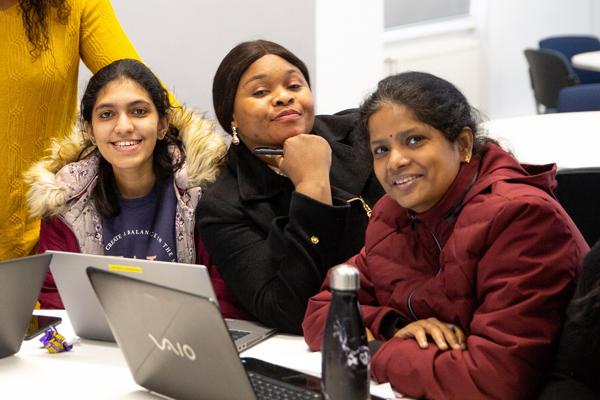 three female students sitting together and looking towards the camera