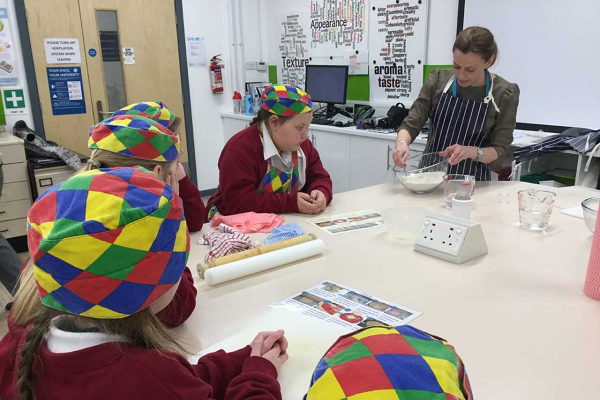school children at a table with chequered hats