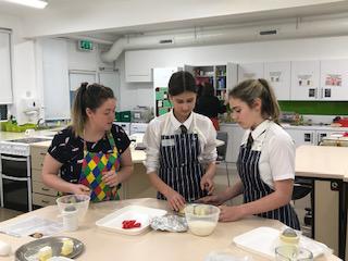 Two pupils and one adult in a kitchen cooking