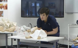 lecturer in a blue top leaning over a cosmetic baby