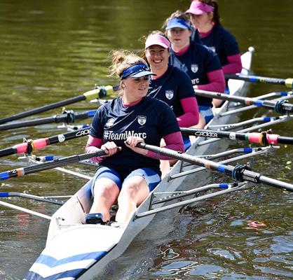 four women in a boat rowing on the water