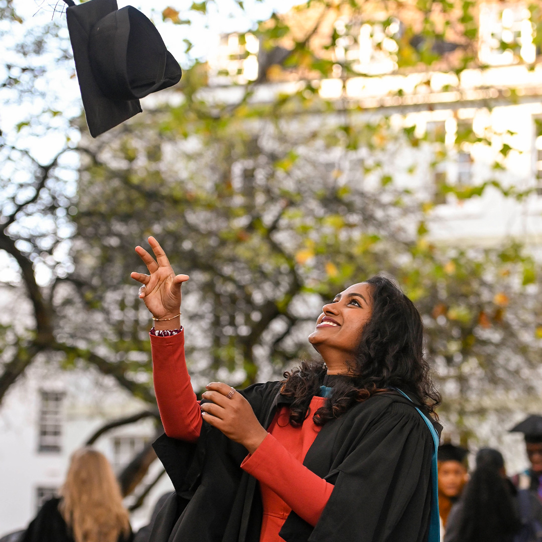 A graduate throwing their cap outside of Worcester Cathedral