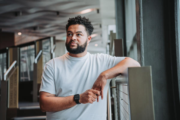 Person poses leaning against railing with stairs behind them