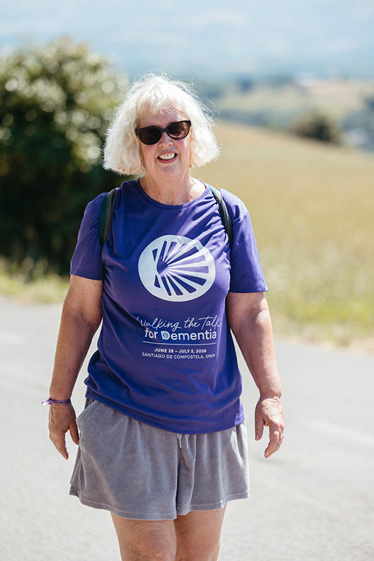 Person walking facing camera, scenery behind