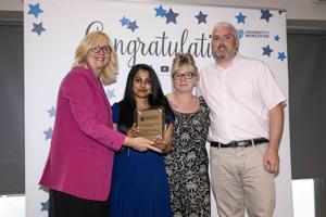 Four people standing in front of a banner holding an award