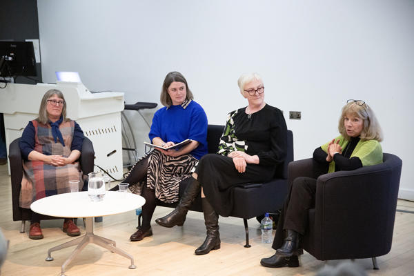 Four people sat on chairs round a table - the person on the far right is speaking