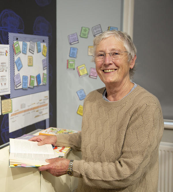 Person holding open a book and looking to the front
