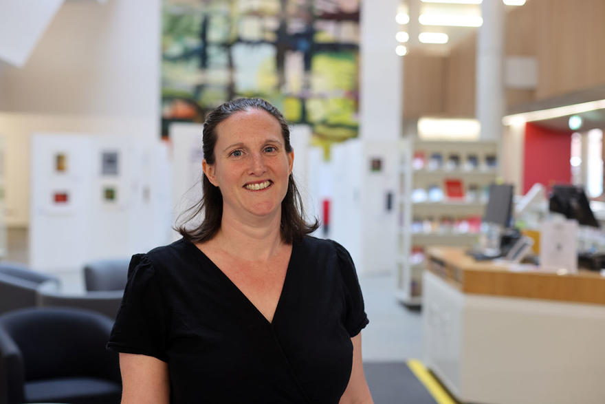Profile photo of person in The Hive library - with mural behind them