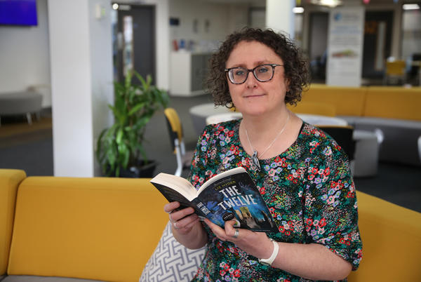 Person sat on couch with open book facing camera