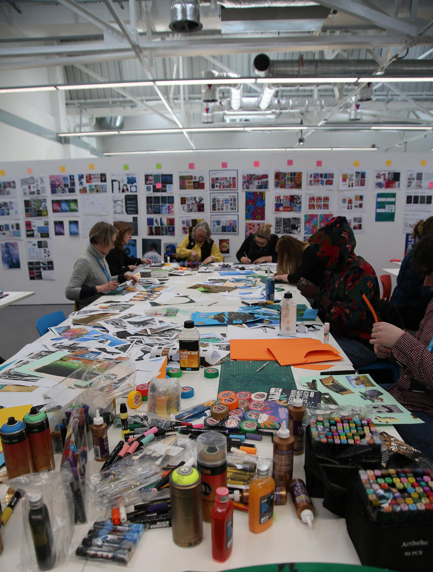 Students at a table with art materials and creating pieces of artwork