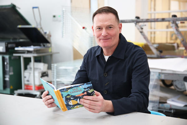 Person sat at table holding open a book