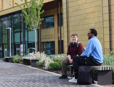 Two students on a bench outside Elizabeth Garrett Anderson building
