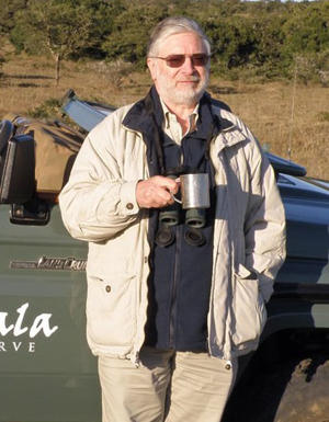 Chris Brown is standing next to a car holding a cup of tea